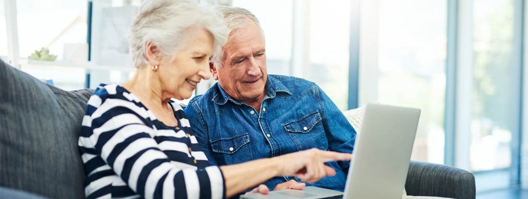 senior couple using a laptop together on the sofa at home