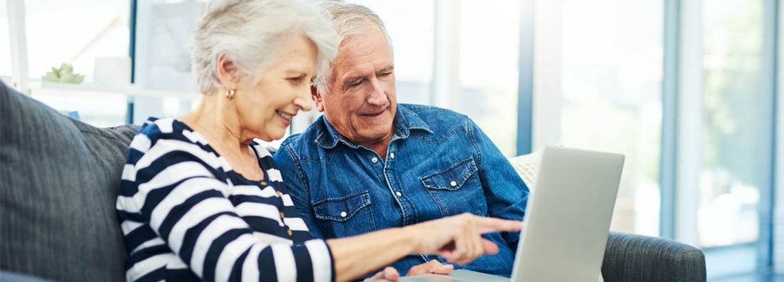 senior couple using a laptop together on the sofa at home