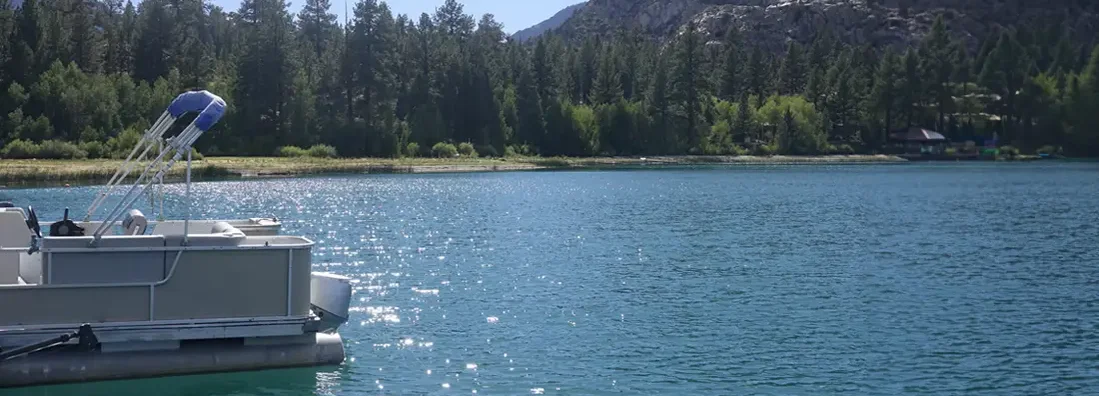 Pontoon boat docked along the shore on a sunny morning. Find Montana Boat Insurance. 