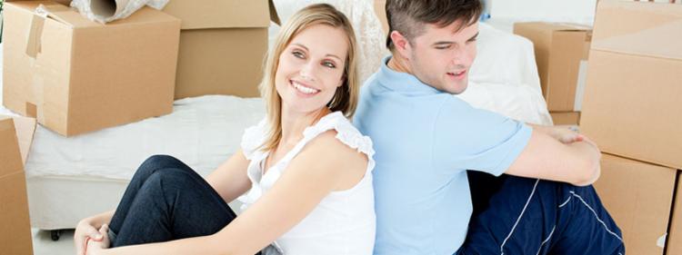 A couple sits among moving boxes in their new home.