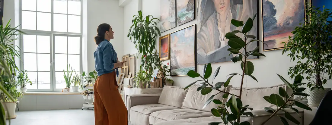 Renter examines portrait artwork among paintings on apartment wall. Does Renters Insurance Cover Collectibles in 2026?