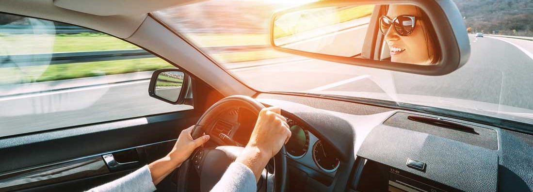 Woman driving car on highway. Find Good Driver Discounts.
