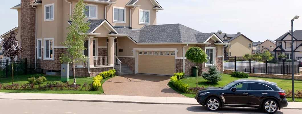 Brand new suburban house and car parked on street on a sunny summer afternoon. Find Tennessee umbrella insurance.