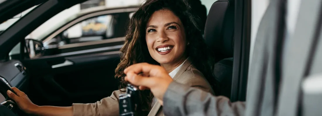 Beautiful woman buying car at showroom. How to Find the Best Car Insurance in Waukee, Iowa.