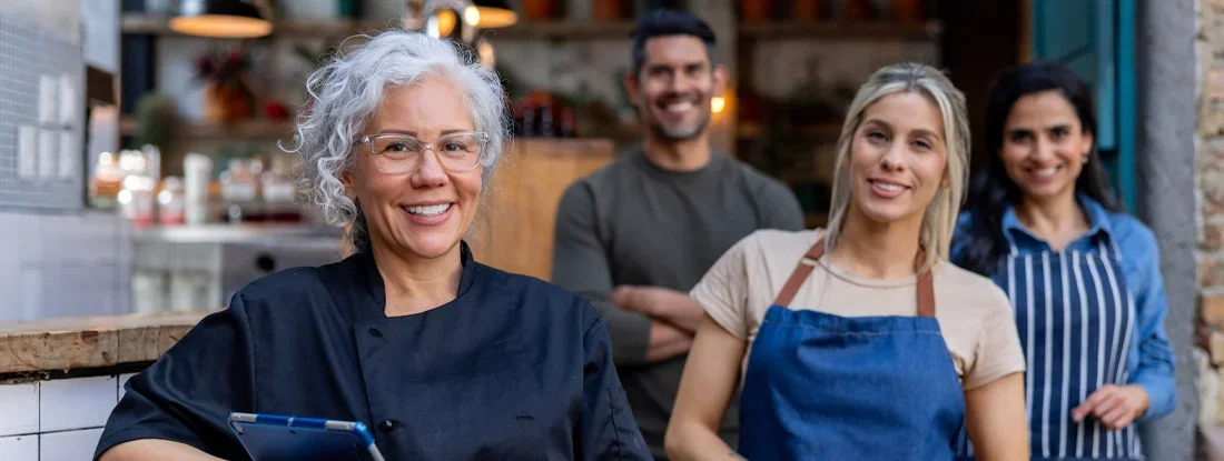 Food service employees working at a restaurant and smiling. Find Contingent Liability Insurance.