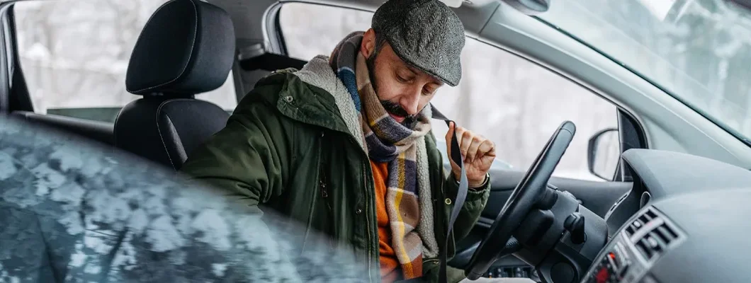 Mature man buckling her seatbelt in car. Is Warming Up Your Car Really Necessary?