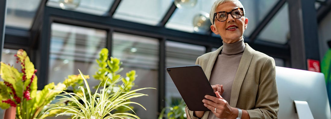 Businesswoman with Short Hair Standing outside and Holding a Digital Tablet. Compare business insurance.