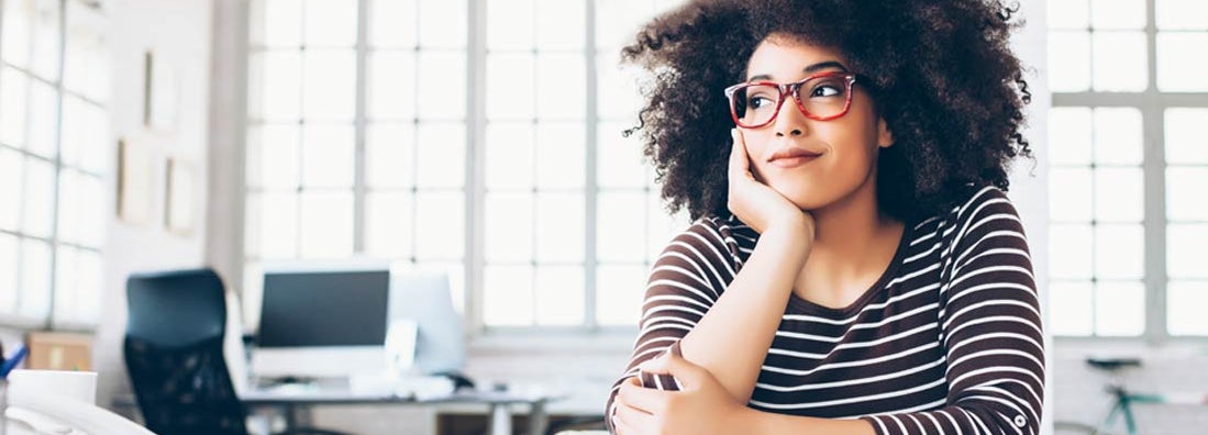 Cheerful young entrepreneur sitting on desk