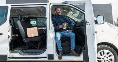 Cheerful Delivery Driver Taking a Break in Van. Find Maryland Commercial Vehicle Insurance.