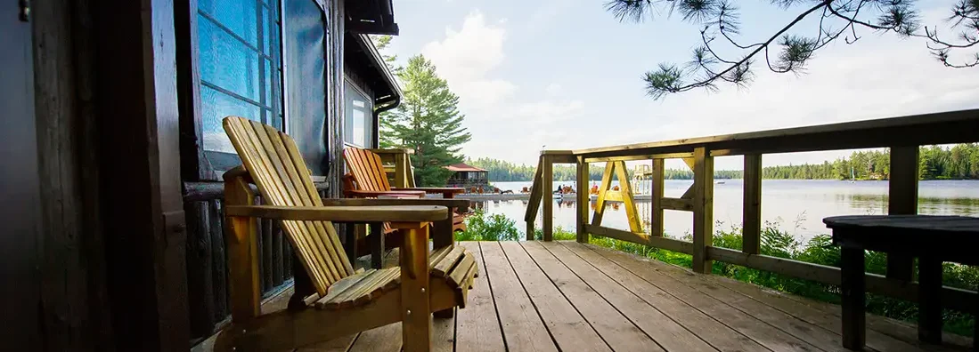 Muskoka chairs on a wooden deck of lake house. Find Lake Oswego, Oregon homeowners insurance.