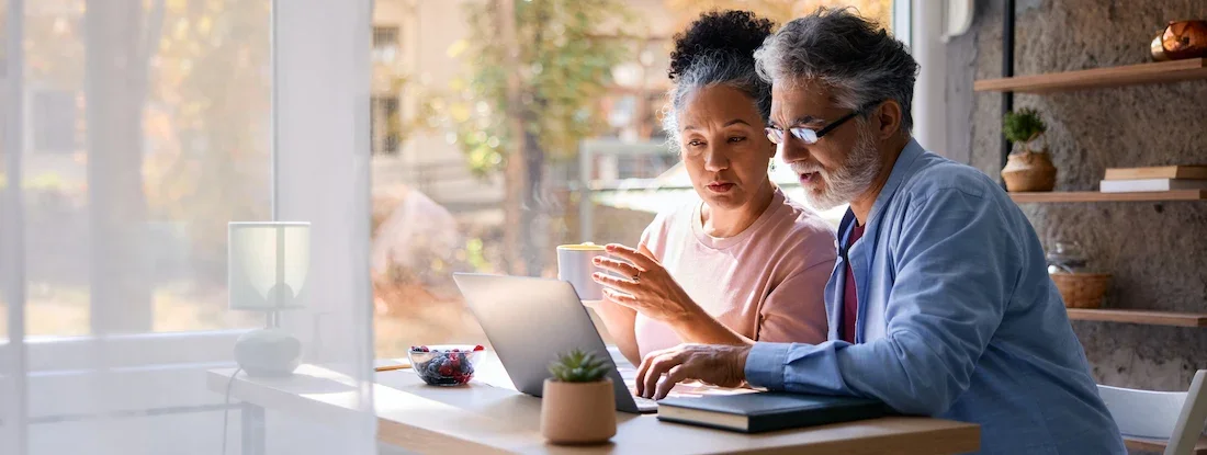 Couple using a laptop discussing financial options. Find Medicare Supplemental Insurance.