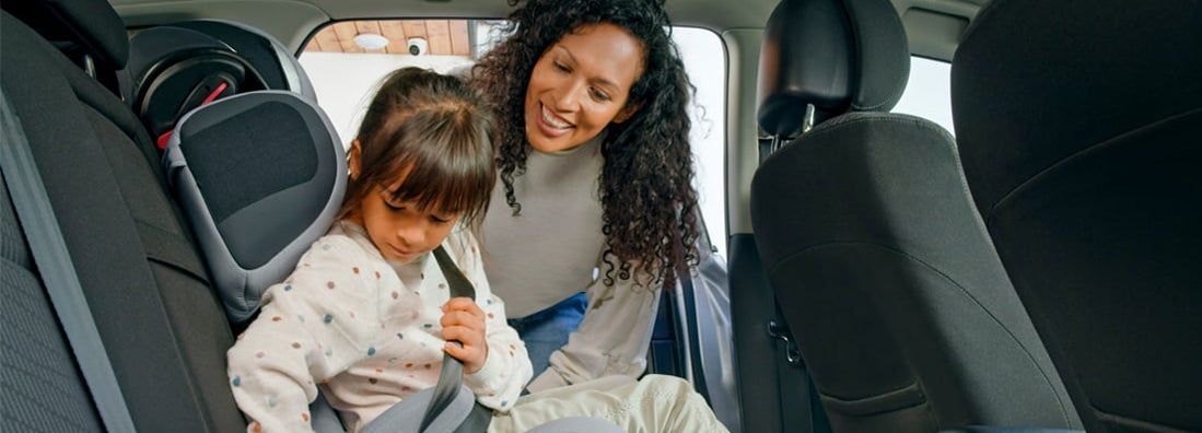 Mother helping daughter while fastening seat belt in car. How to Find the Best Car Insurance Coverage in West Fargo, North Dakota.