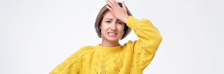 Young woman in yellow sweater holding her head because she forgot to get butter