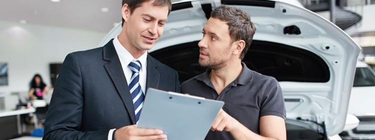 A man questioning his car dealer on some paperwork.