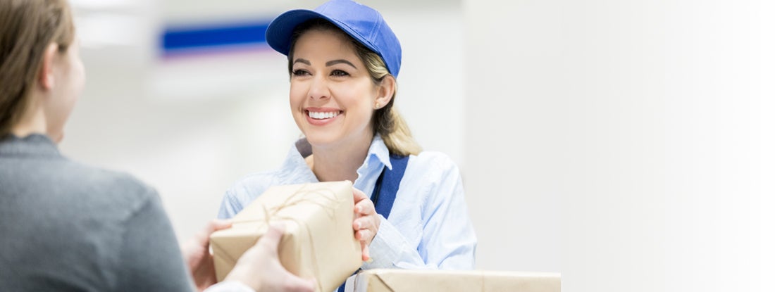 A female postal worker accepts a package at post office.