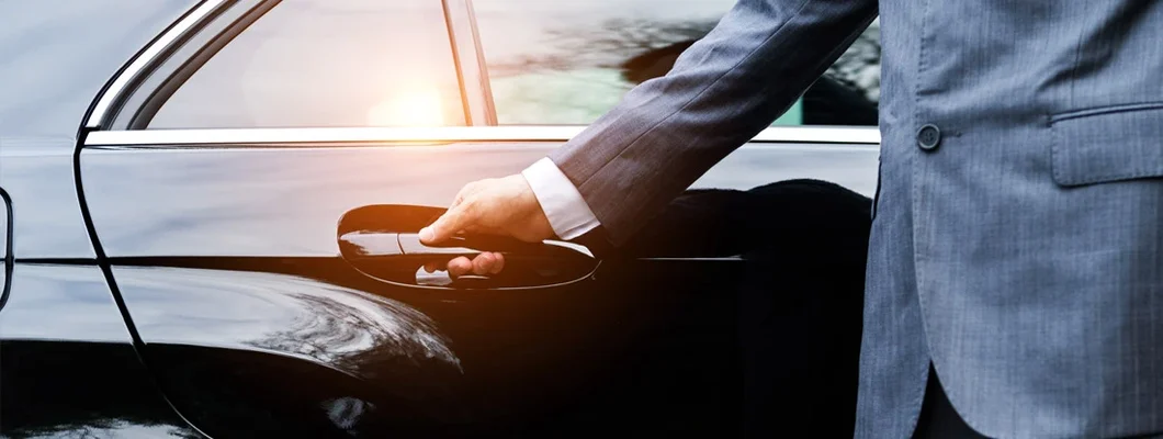 Closeup of a doorman opening a car door. Find Black Car and Limo Insurance.