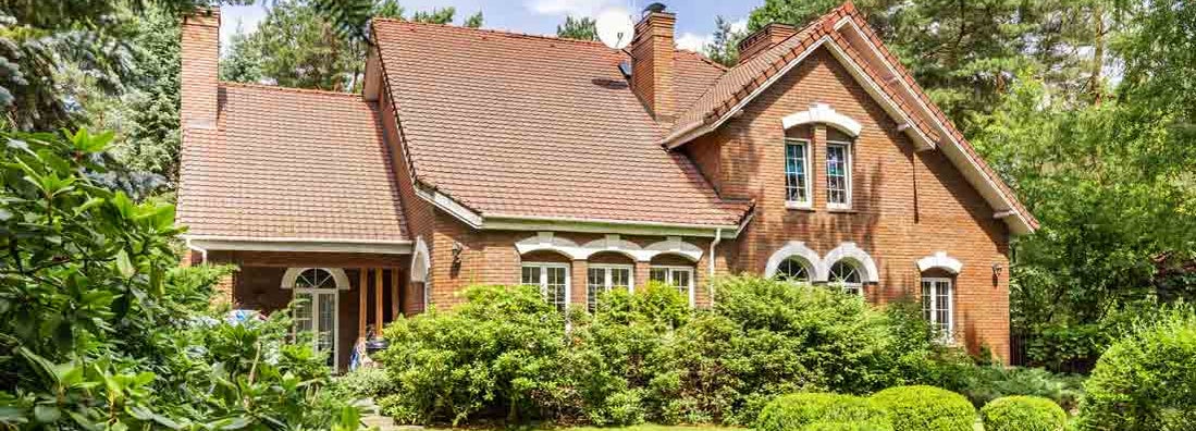 Backyard of a beautiful english style house with bushes and green lawn. Find HO8 Homeowners Policy Insurance.