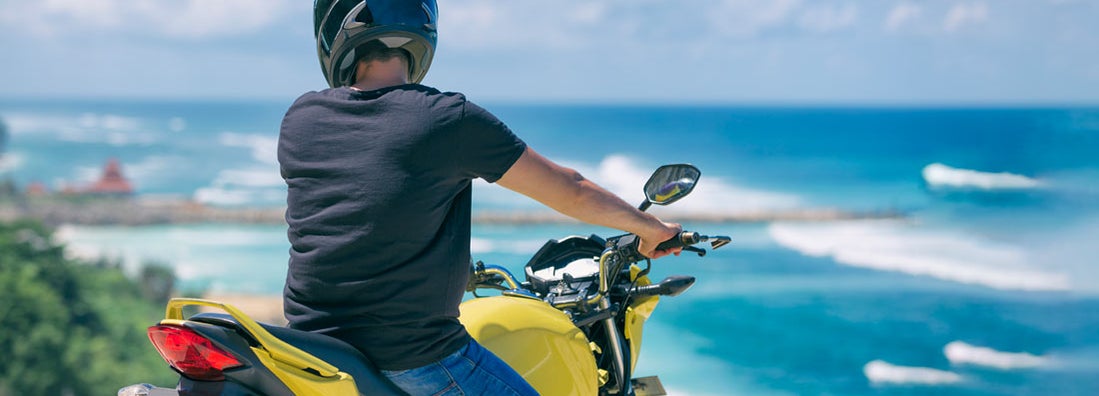 Man sitting on motorcycle on Hawaii beach. Find Hawaii Motorcycle Insurance.