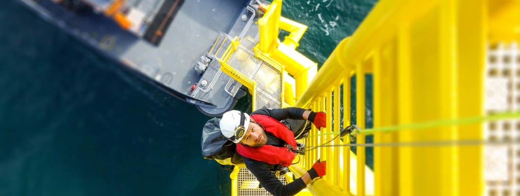Manual high worker offshore climbing on wind-turbine on ladder. Find workers compensation FAQs.