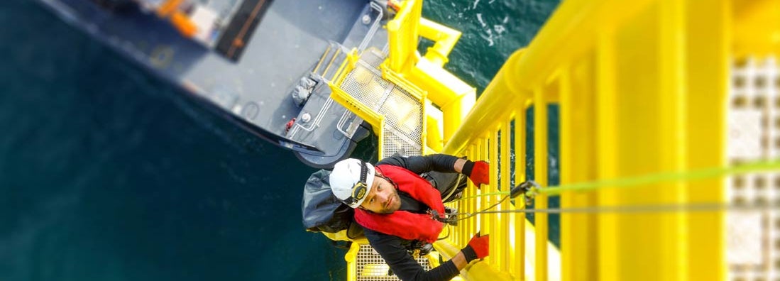 Manual high worker offshore climbing on wind-turbine on ladder. Find workers compensation FAQs.