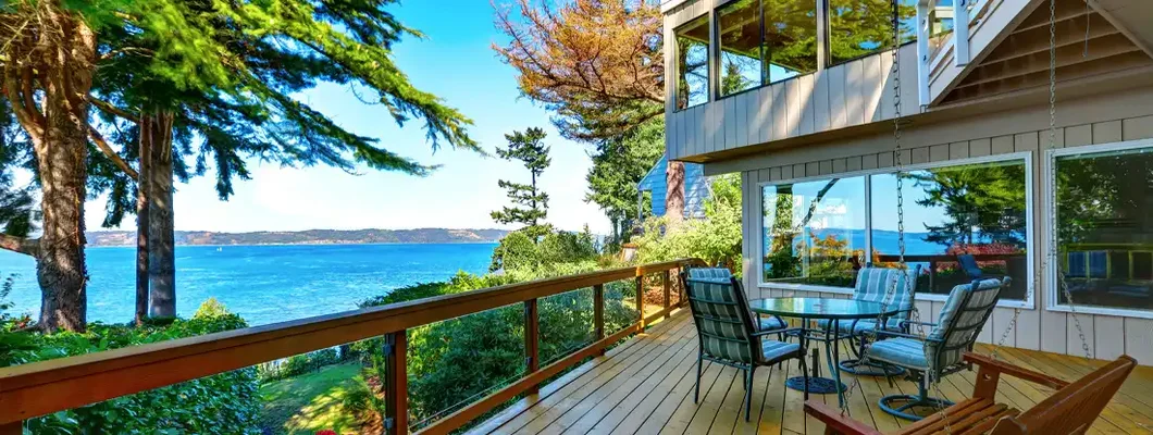 Wooden walkout deck with outdoor table set and swinging bench at lake house. Seven Essential Considerations Before Buying That Gorgeous Lake House.