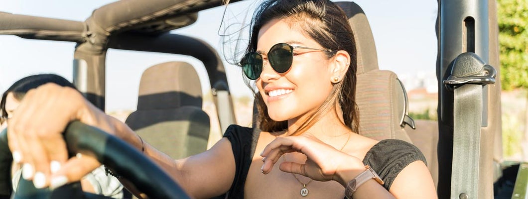 Happy woman driving SUV during summer trip. Find Albuquerque, New Mexico car insurance.