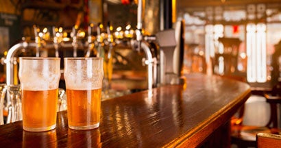 Two ice cold glasses of beer on wooden counter of bar. Find the best bar insurance with an independent insurance agent.