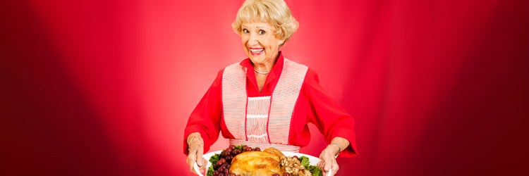 Sweet grandmother holding a beautifully cooked turkey dinner.