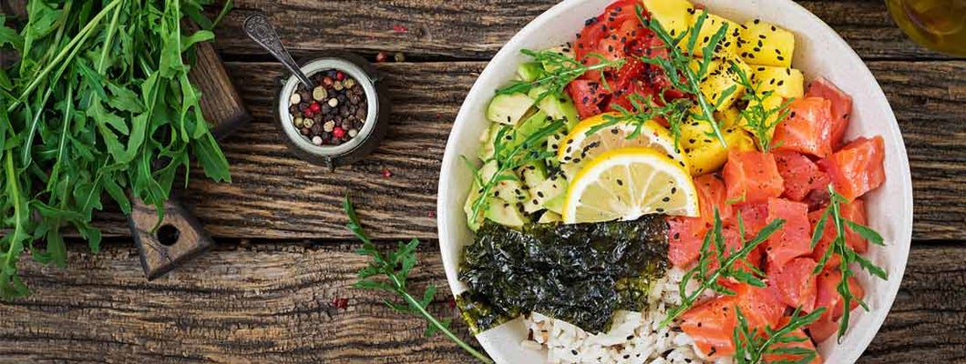 Hawaiian salmon fish poke bowl with rice, avocado, mango, tomato, sesame seeds and seaweed.