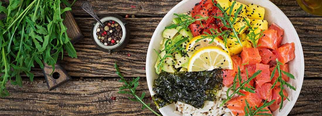 Hawaiian salmon fish poke bowl with rice, avocado, mango, tomato, sesame seeds and seaweed.