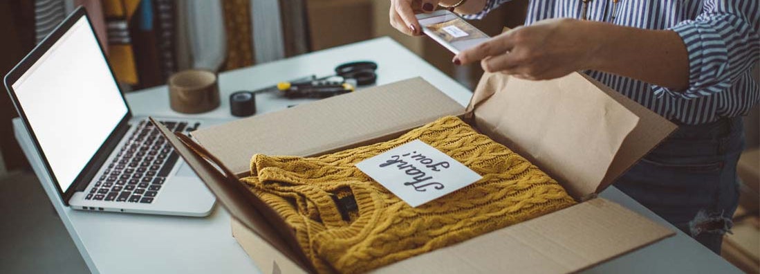 Small business owner packing product in boxes, preparing it for delivery.