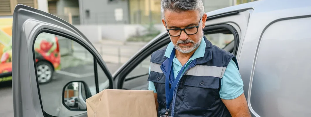 Delivery man holding cardboard box and unloading parcel for delivery. Find South Carolina Commercial Vehicle Insurance.