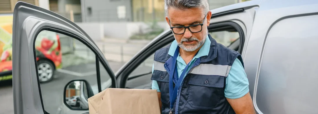 Delivery man holding cardboard box and unloading parcel for delivery. Find South Carolina Commercial Vehicle Insurance.