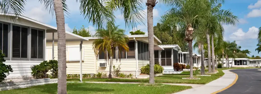 Mobile home park with palm trees and sidewalk. Find Mobile Home Insurance Cost.