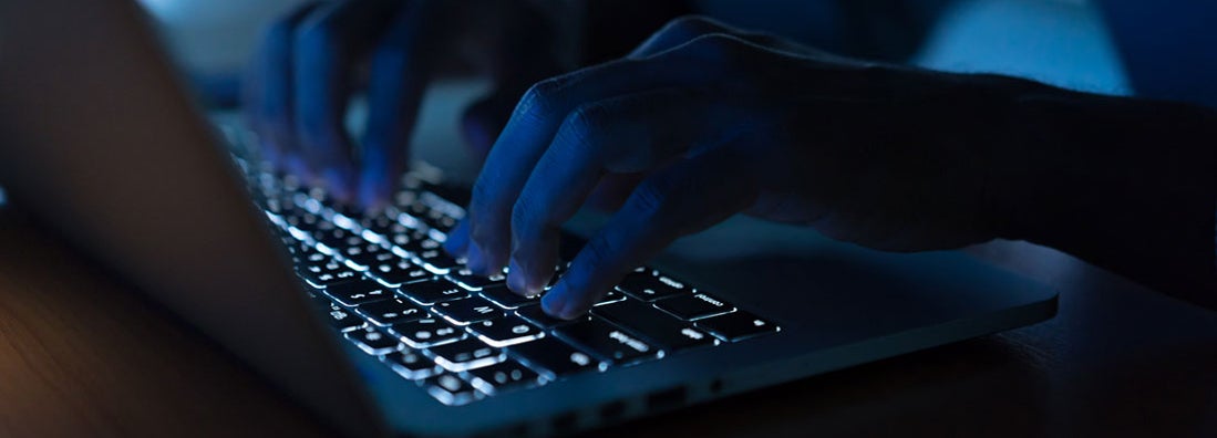 Programmer man hand typing on keyboard laptop. Commercial Crime Insurance.