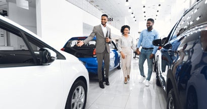 Salesman Showing Luxury Car to Couple at Auto In Dealership. What Car Should I Buy?