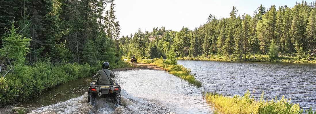 People driving ATV quads through water. Find ATV Insurance.