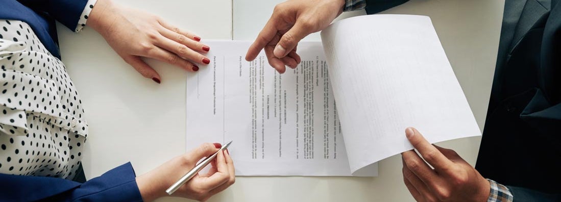 Woman signing contract at meeting, view from above. Find Notary Insurance.