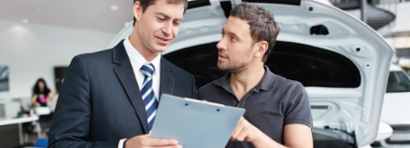 A man questioning his car dealer on some paperwork.