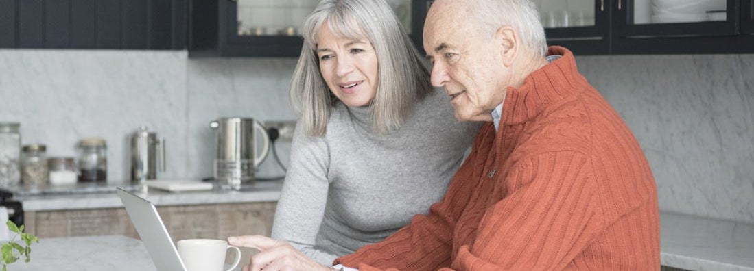 Senior man and woman using laptop at home together 
