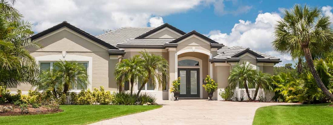 New luxury home in Miami with driveway, palm trees, lush tropical foliage, front lawn. Find Miami Florida homeowners insurance.