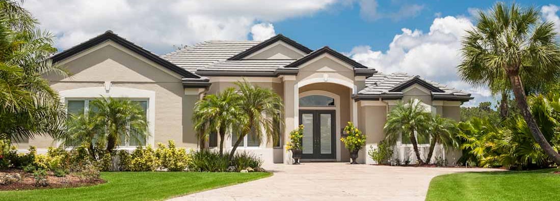 New luxury home in Miami with driveway, palm trees, lush tropical foliage, front lawn. Find Miami Florida homeowners insurance.