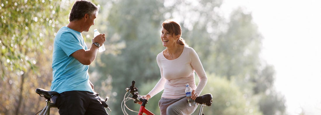 Couple with bicycles drinking water in city park. Find Philadelphia Pennsylvania life insurance.