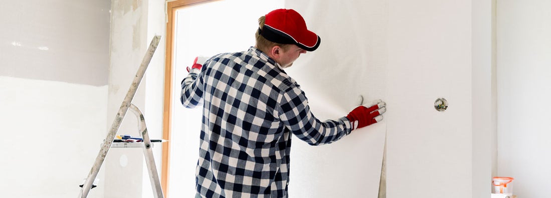 Contractor is putting up wallpapers on the wall. Find wall covering contractor insurance.