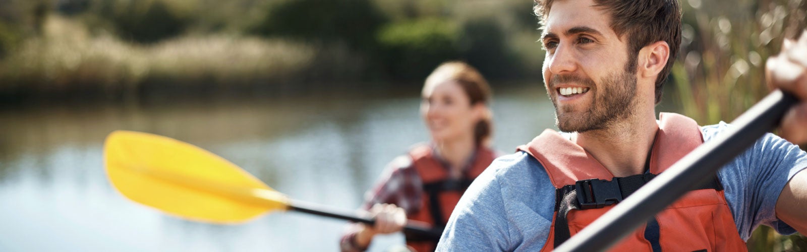 Young couple kayaking together on a lake. Find RLI Insurance.