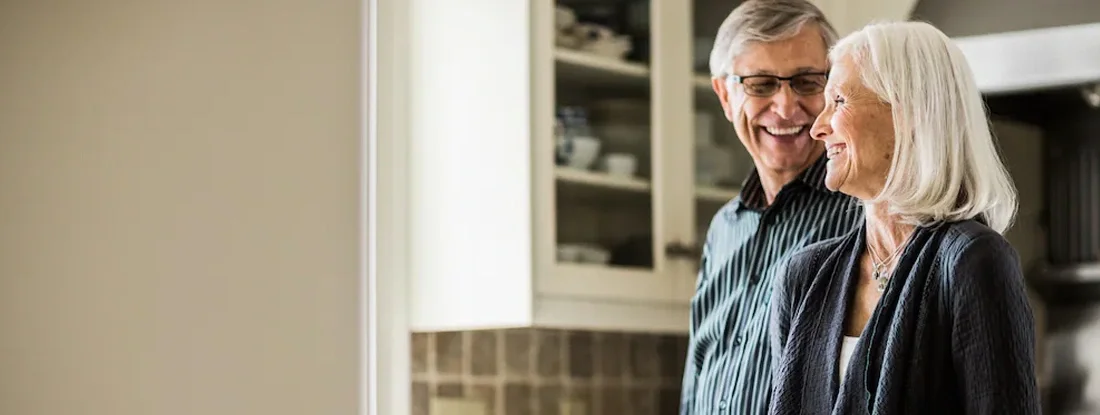 Senior couple laughing in kitchen. Medicare Part D Health Supplements: What to Know.