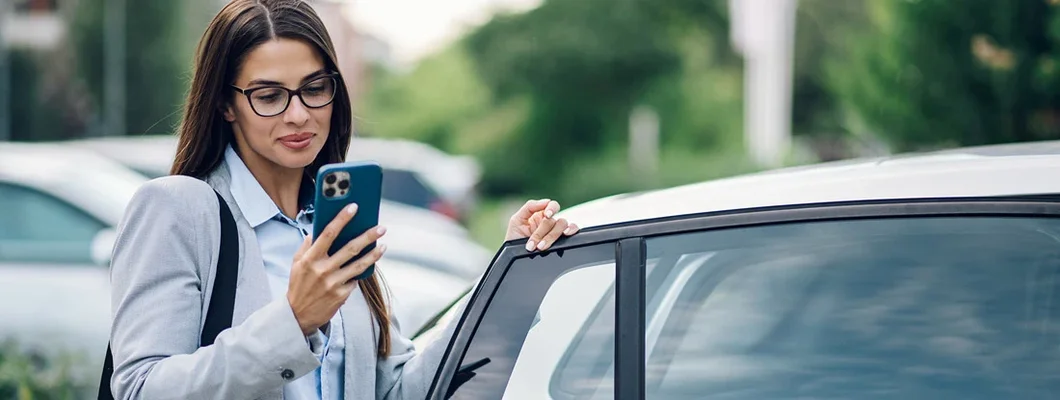 Business woman getting into the car and using phone. Best Car Insurance for Government Employees. 