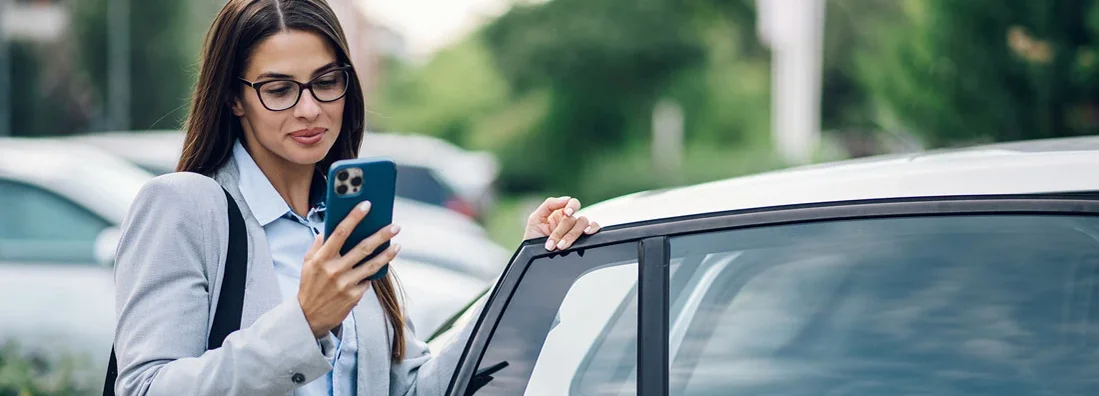 Business woman getting into the car and using phone. Best Car Insurance for Government Employees.