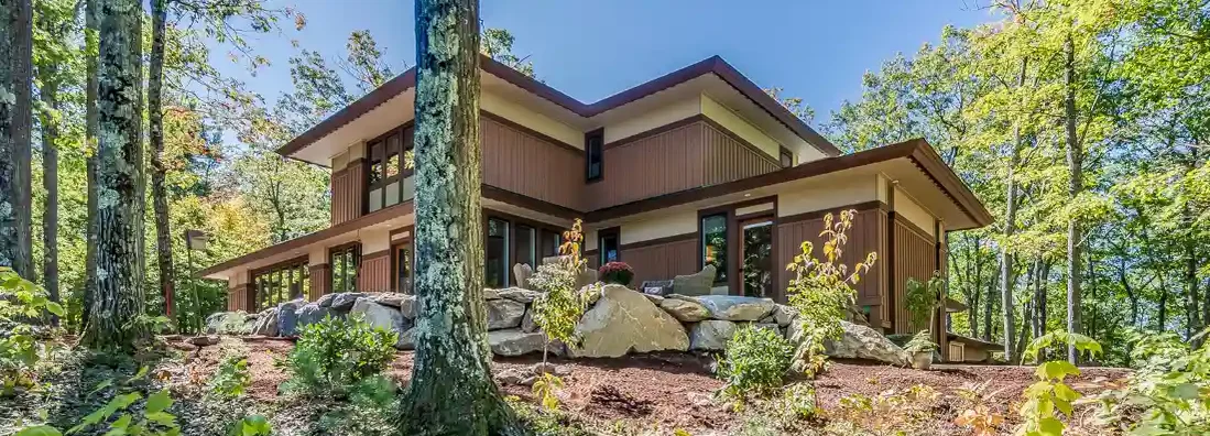 Beautiful clear day and a home surrounded by tall skinny trees. Jackson, Wyoming Homeowners Insurance.