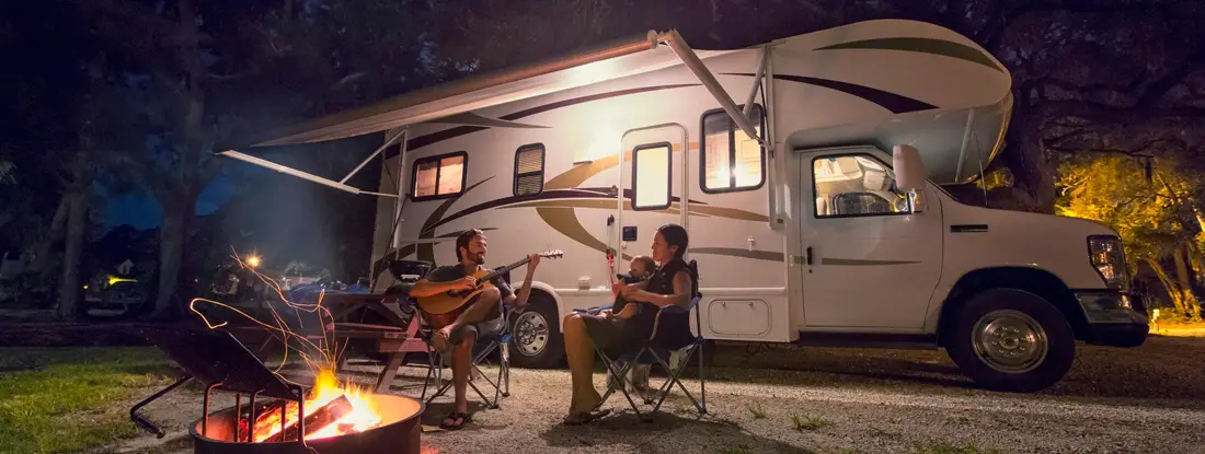 Couple and baby daughter sitting in front of campfire at night. The Best-Kept Secret in Savannah for RVers.